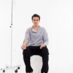 Cure Adaptive Chemotherapie-Behandlungskleidung – Graue Herrenansicht im Sitzen mit Infusion