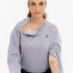 Cure Adaptive Chemotherapie-Behandlungskleidung – Graue Damenansicht mit geöffneter Brustöffnung, Infusionsleitung und medizinischem Zugang