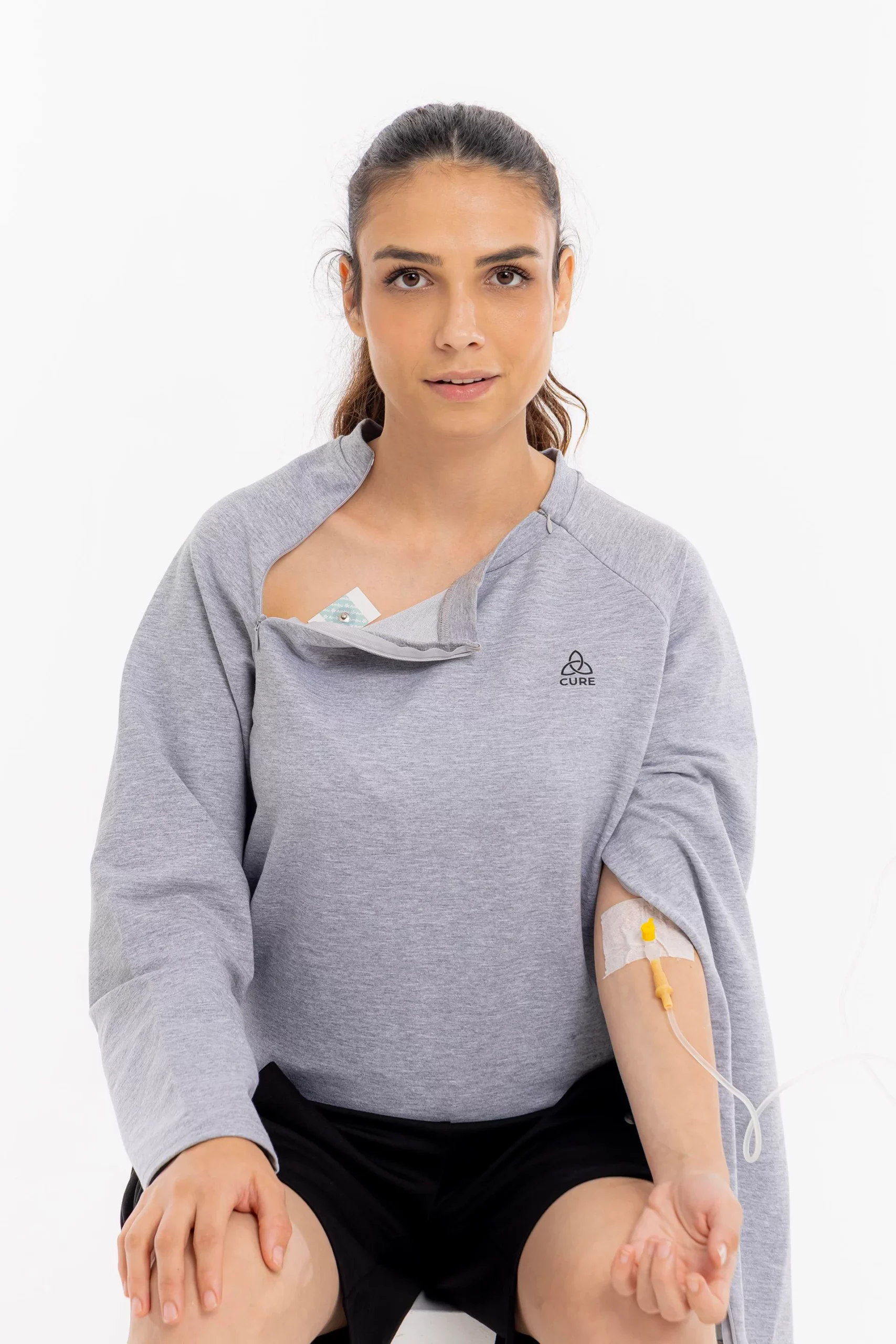 Cure Adaptive Chemotherapie-Behandlungskleidung – Graue Damenansicht mit geöffneter Brustöffnung, Infusionsleitung und medizinischem Zugang