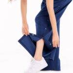 Frau zeigt Funktion der orthopädischen Behandlungshose mit seitlichem Druckknopfverschluss in Blau – für Reha und postoperative Pflege geeignet