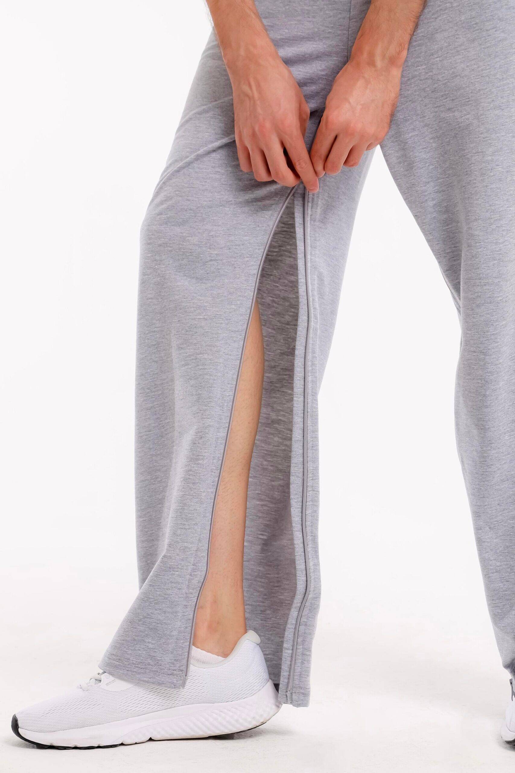 Detailansicht der Pflegehose mit geöffnetem Reißverschluss, der an der Seite heruntergezogen wird.