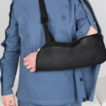 Seitenansicht des Cure Adaptive Pflegeoberteils in Blau mit Armverband und Schultergurt für zusätzlichen Halt, ideal für Patienten nach einer Operation.