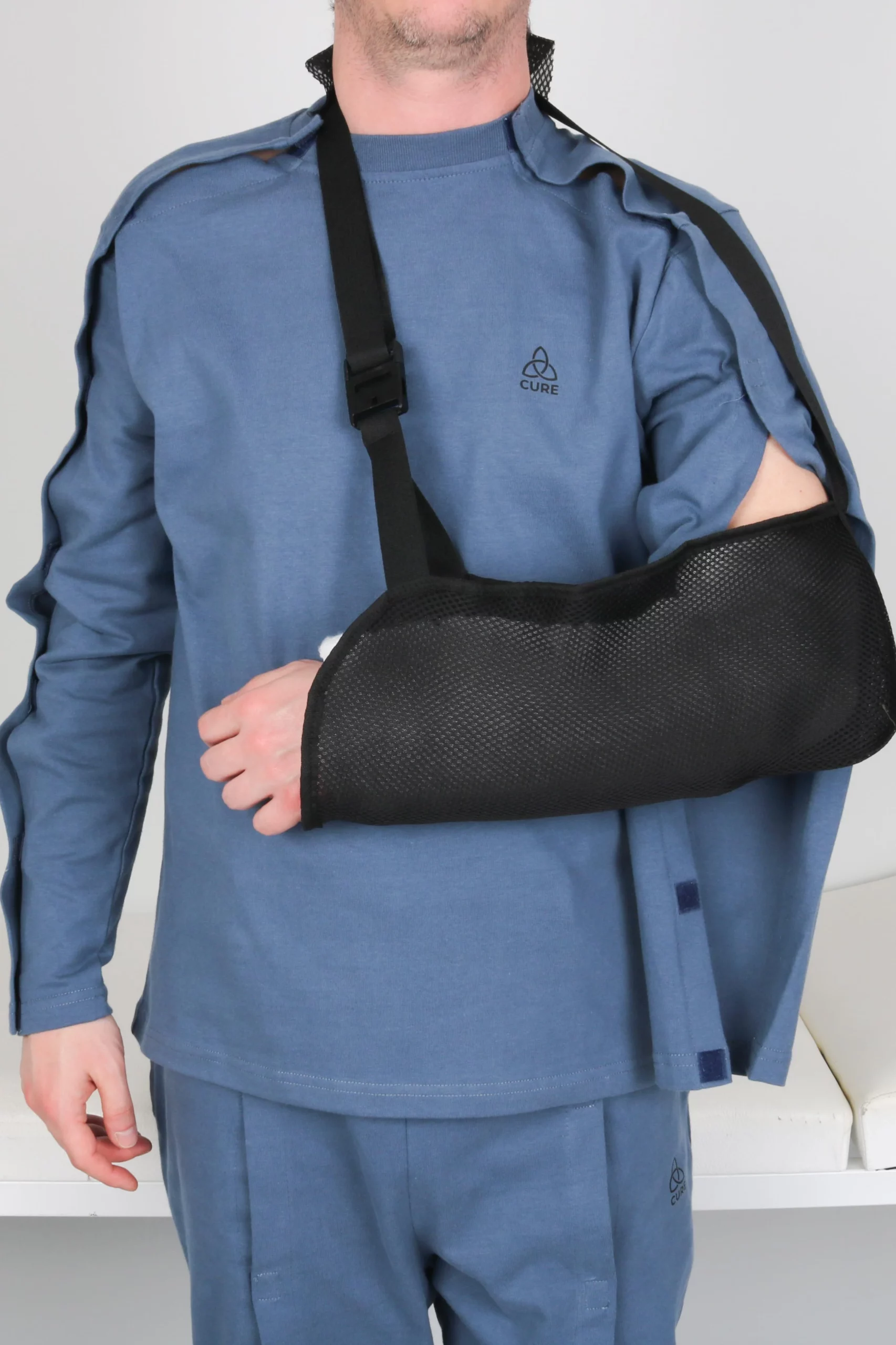 Seitenansicht des Cure Adaptive Pflegeoberteils in Blau mit Armverband und Schultergurt für zusätzlichen Halt, ideal für Patienten nach einer Operation.